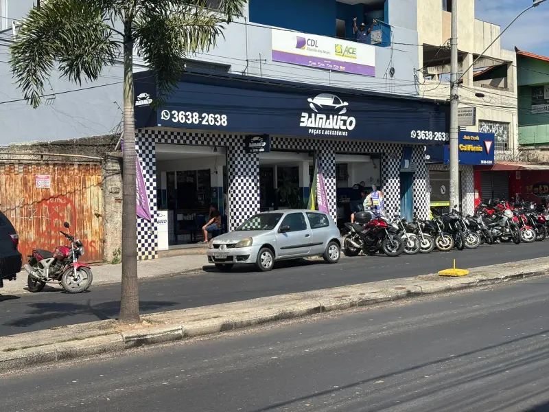 Fachada da Bamauto vista do outro lado da avenida, com letreiro azul e motos estacionadas