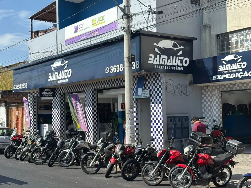 Fachada da Bamauto vista da rua, com letreiro azul, telefone 3638-2638 e motos estacionadas